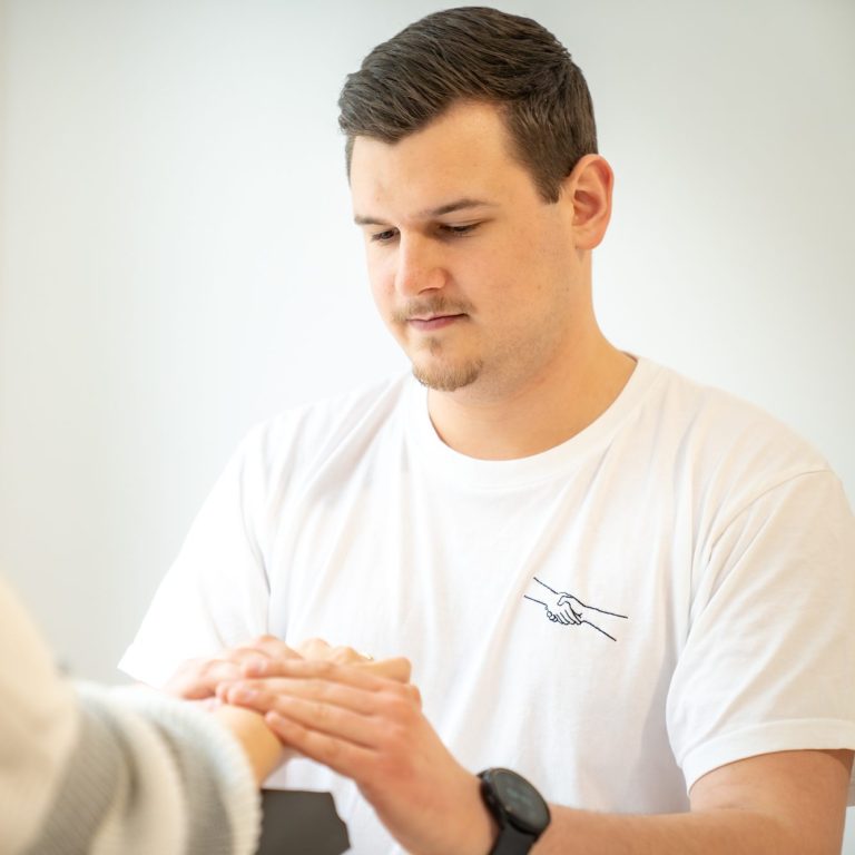 Felix Wernhart BSc - Ergotherapeut in Wien 1030, führt Handtherapie mit einer Patientin durch, Fokus auf Rehabilitation nach Handverletzung